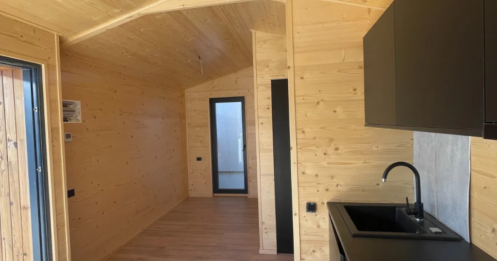 houten chalet van binnen, zwart afewerkte keuken, glazen deuren, schuifpui van glas