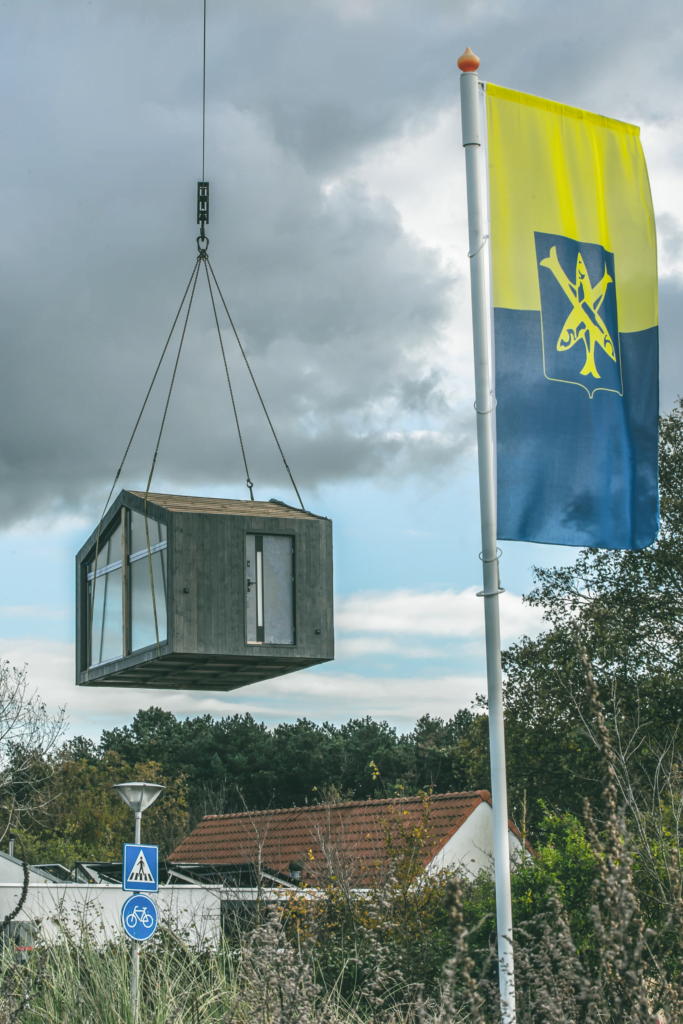 Modulair huis wat is opgehesen door een hijskraan, bewolkte lucht, zandvoortse vlag