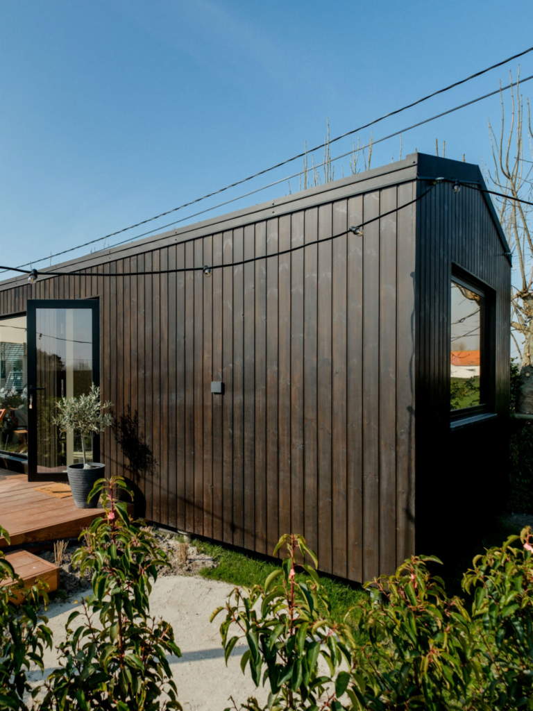 Modern, houten exterieur van een huis met twee niveaus, gelegen in een rustieke tuin met volwassen beplanting