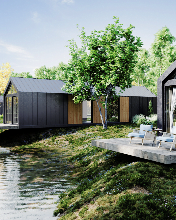 Meerdere tiny houses met donkere metalen daken en houten panelen, gelegen bij een rustig vijvertje met buitenzitjes