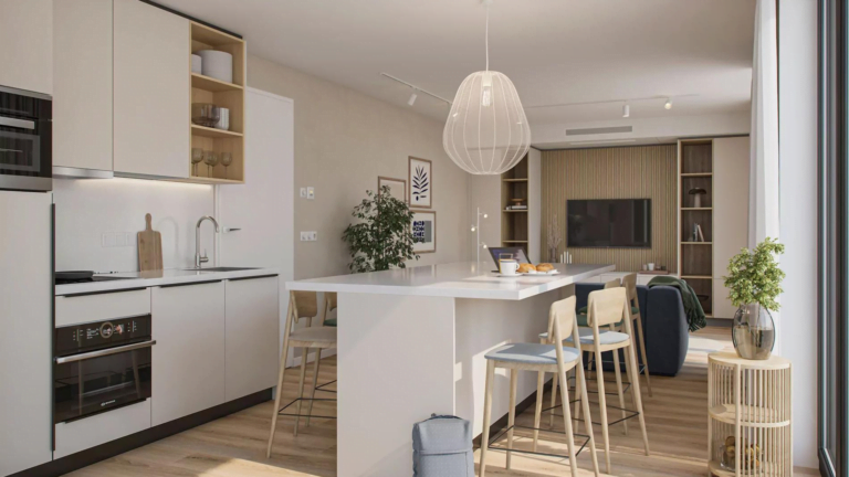 Modern en ruim interieur van een tiny house met een strakke witte keuken voorzien van ingebouwde apparatuur en een open woonruimte. Een stijlvolle hanglamp verlicht de kamer waarin minimalistische decoraties het luchtige gevoel versterken