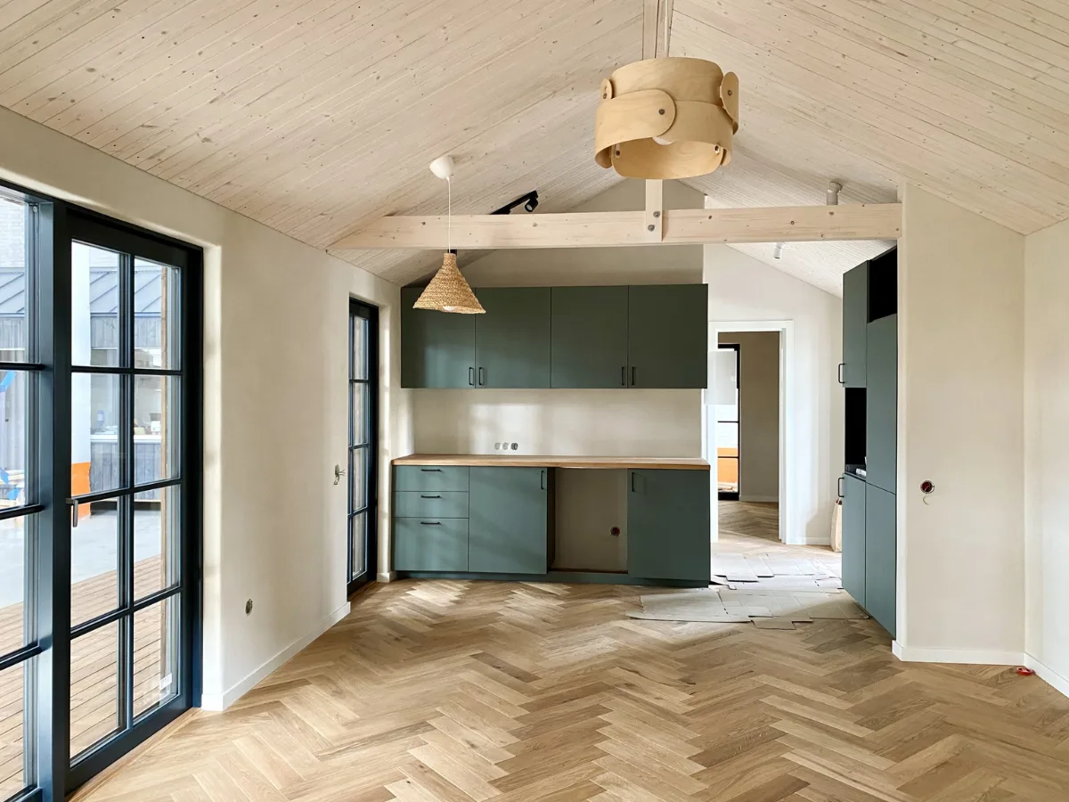 Modern interieur van een houten Tiny House met grote ramen, licht houten vloer, compacte keuken en een warme, minimalistische inrichting, wandafwerking van leemstuc.