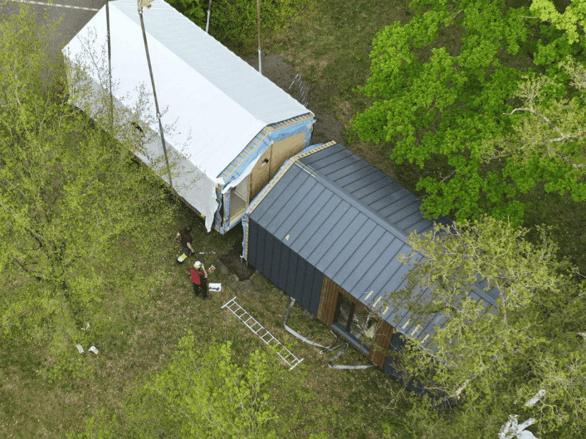 Tiny House wordt met een hijskraan op de juiste plek geplaatst naast een woning