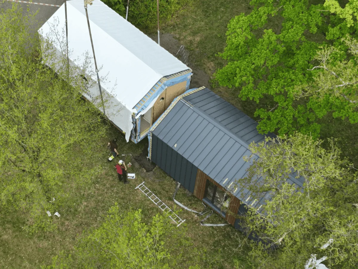 Tiny House wordt met een hijskraan op de juiste plek geplaatst naast een woning