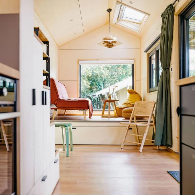 Licht interieur van een moderne familiewoning met zithoek, grote ramen en houten afwerking